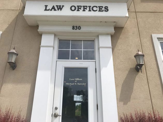 The entrance to a law office building at address 830, featuring white door frames, a glass door, and two wall lamps.