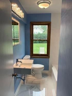 A bathroom with a sink , toilet , and window.