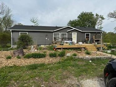 A mobile home with a deck and a car parked in front of it.