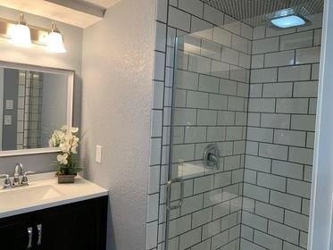 A bathroom with a walk in shower and a sink.