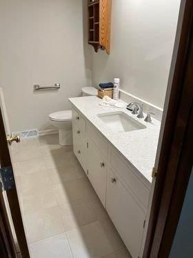 A bathroom with a toilet , sink , and cabinets.