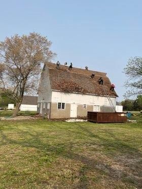 A group of people are working on the roof of a barn.