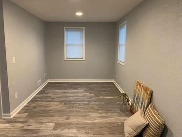 An empty room with a wooden floor and two windows.