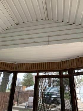 A sun room with a white ceiling and a lot of windows.