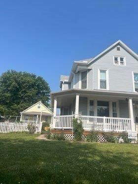 A large white house with a large porch and a white picket fence.
