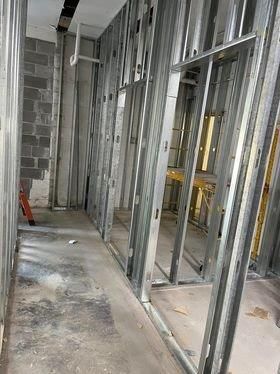 A hallway in a building under construction with metal frames and brick walls.