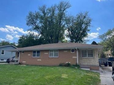 A brick house with a roof and a car parked in front of it.