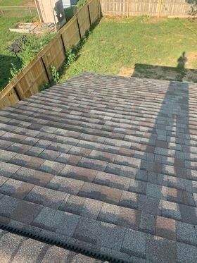 A roof with a wooden fence in the background and a shadow of a person on it.