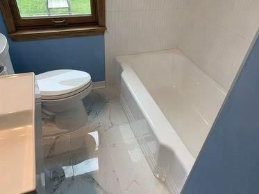 A bathroom with a toilet , sink and bathtub.