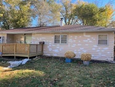 A white house with a wooden deck and flowers in front of it.
