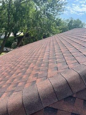 A close up of a red roof with trees in the background.