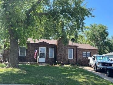 A brick house with two cars parked in front of it.