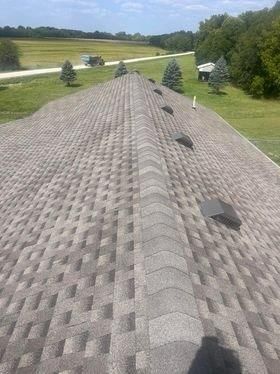 A large roof with a lot of shingles on it is sitting on top of a lush green field.