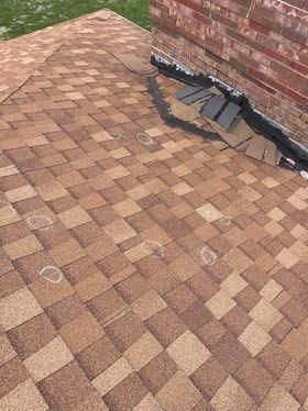 A close up of a roof with a brick wall in the background.