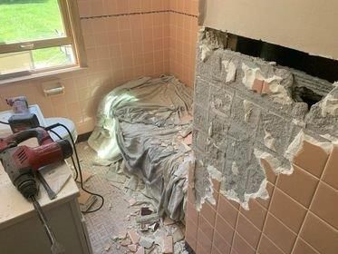 A bathroom with a hole in the wall and a drill.