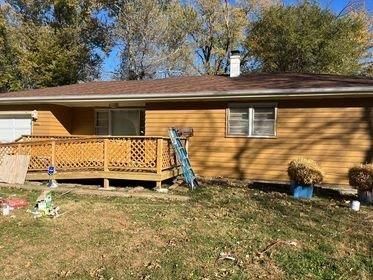 A house with a deck and a ladder in front of it.