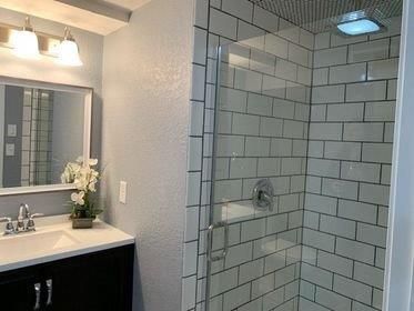 A bathroom with a walk in shower and a sink.