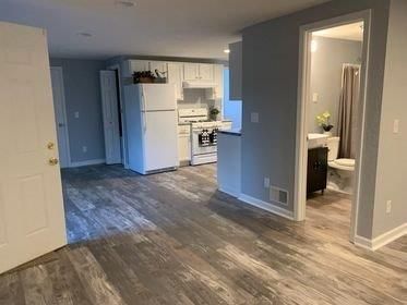 A kitchen with a refrigerator , stove , sink , and toilet.