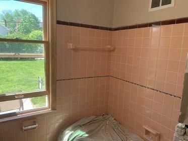 A bathroom with pink tiles and a window.