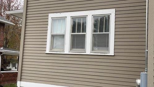 A house with three windows on the side of it.