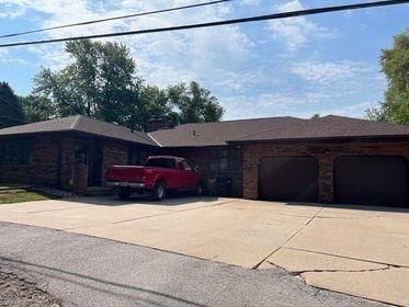 A red truck is parked in front of a brick house.