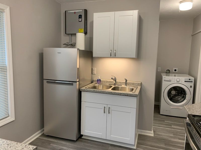 A kitchen with a refrigerator , sink , washer and dryer.