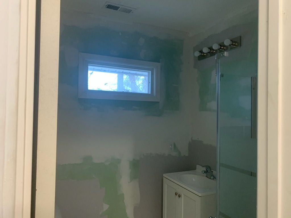 A bathroom with a sink , mirror , and window.