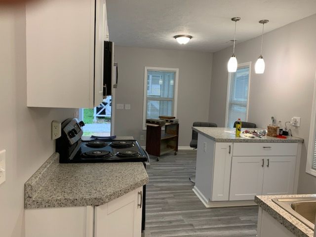 A kitchen with a stove , sink , and cabinets.