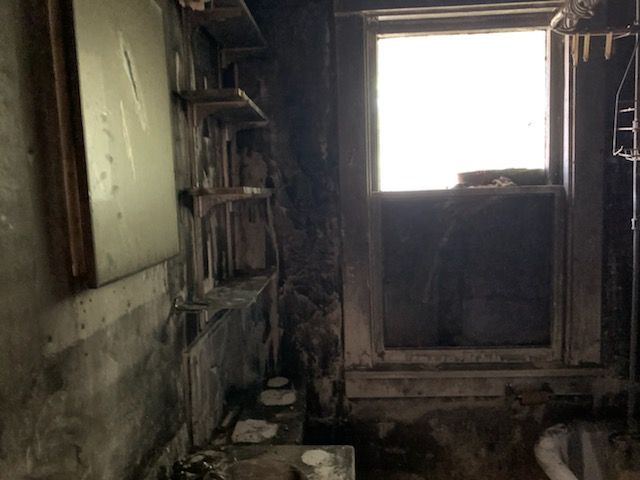 A dark room with a window and shelves.