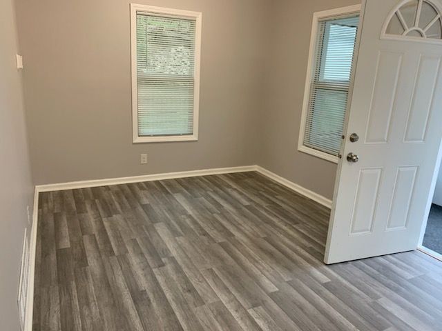 An empty room with hardwood floors and a white door.