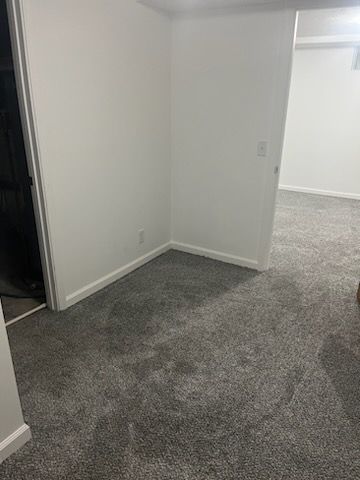 An empty room with a gray carpet and white walls.