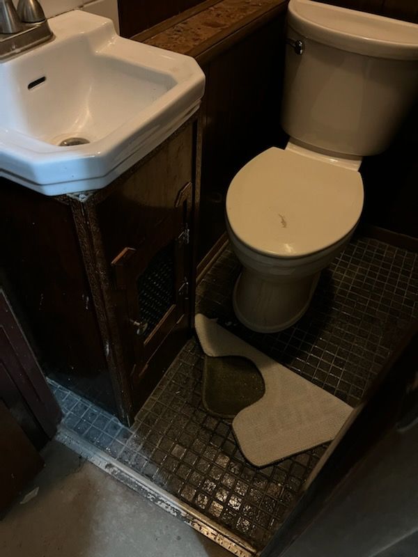 A bathroom with a toilet a sink and a towel on the floor