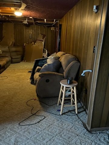 A living room with a couch and a stool in it.