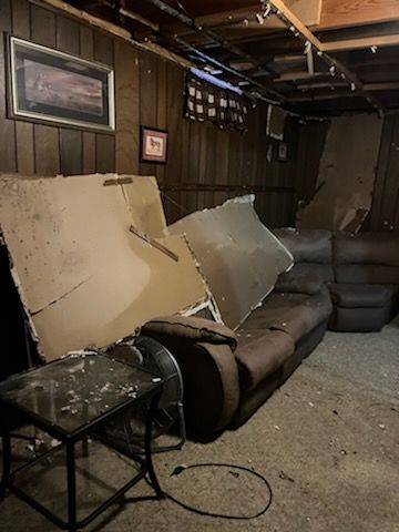 A room with a couch , chairs , a table and a picture on the wall.