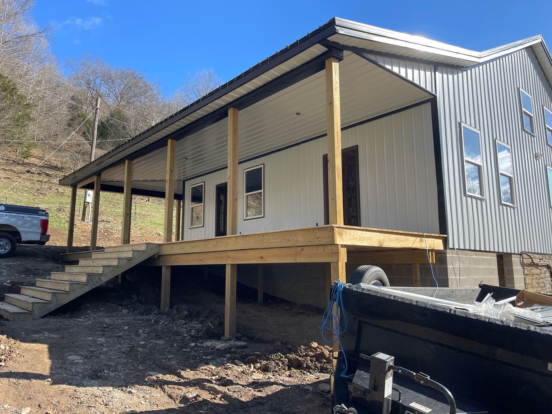 A white house with a porch and a truck parked in front of it.