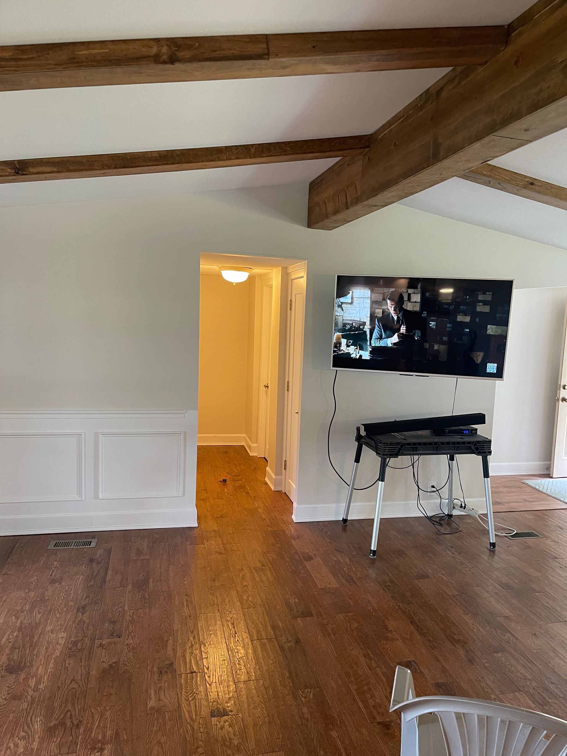 A living room with hardwood floors and a flat screen tv on the wall.