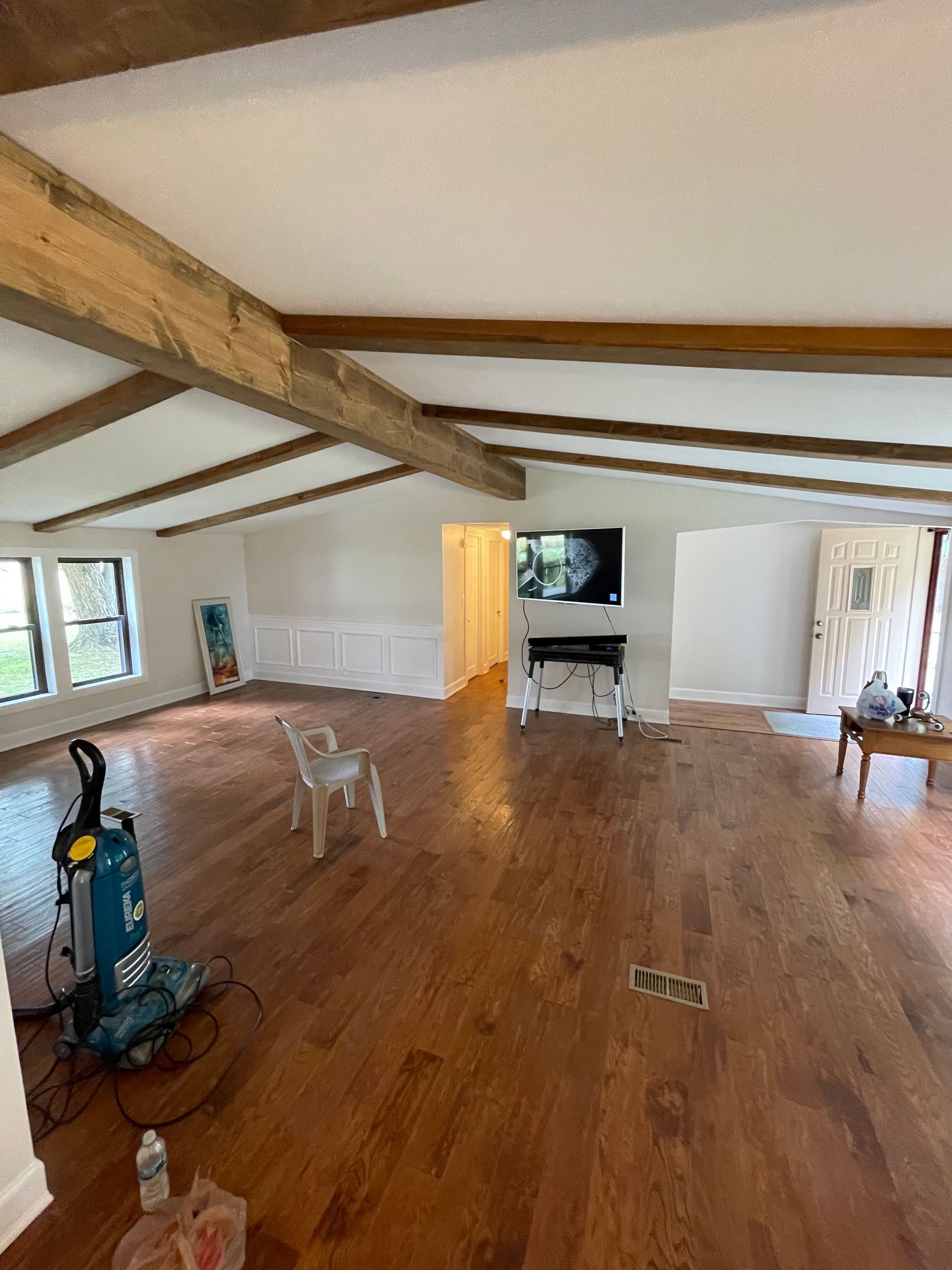 A living room with hardwood floors and a vacuum cleaner in it.