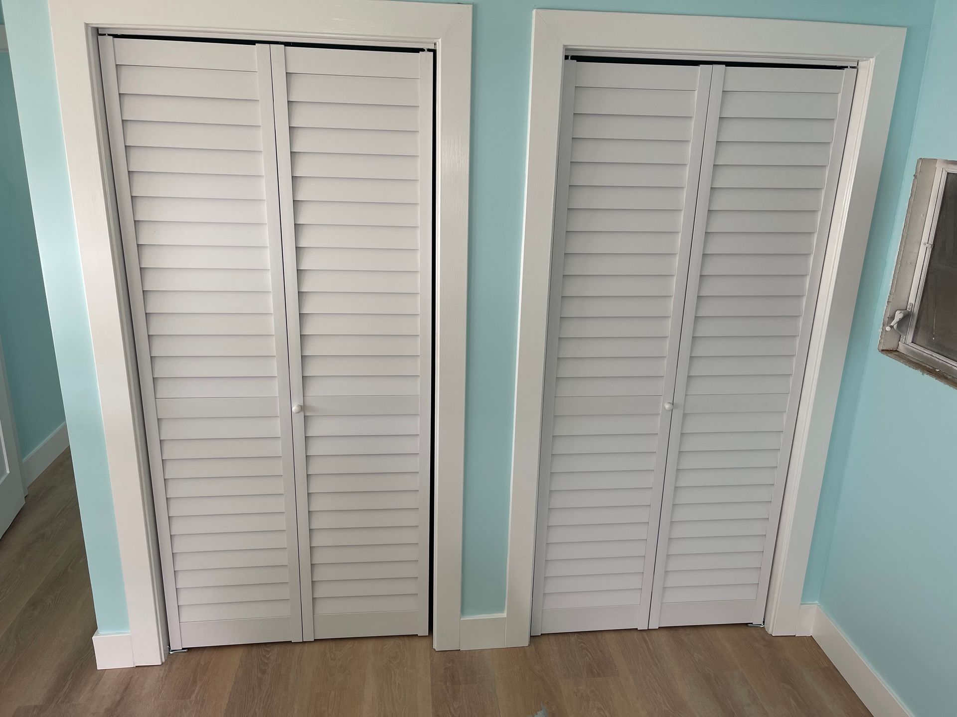 Two white shutters are open in a room with blue walls.