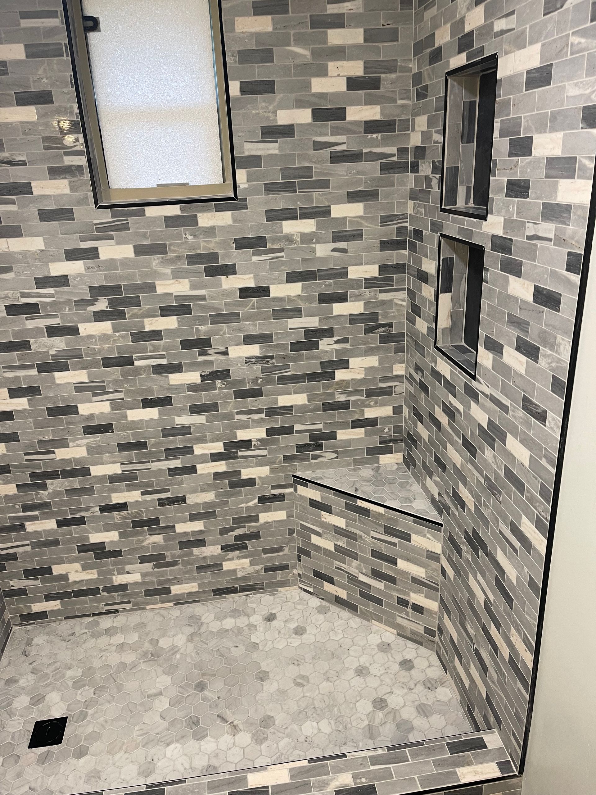 A bathroom with a walk in shower and a brick wall.
