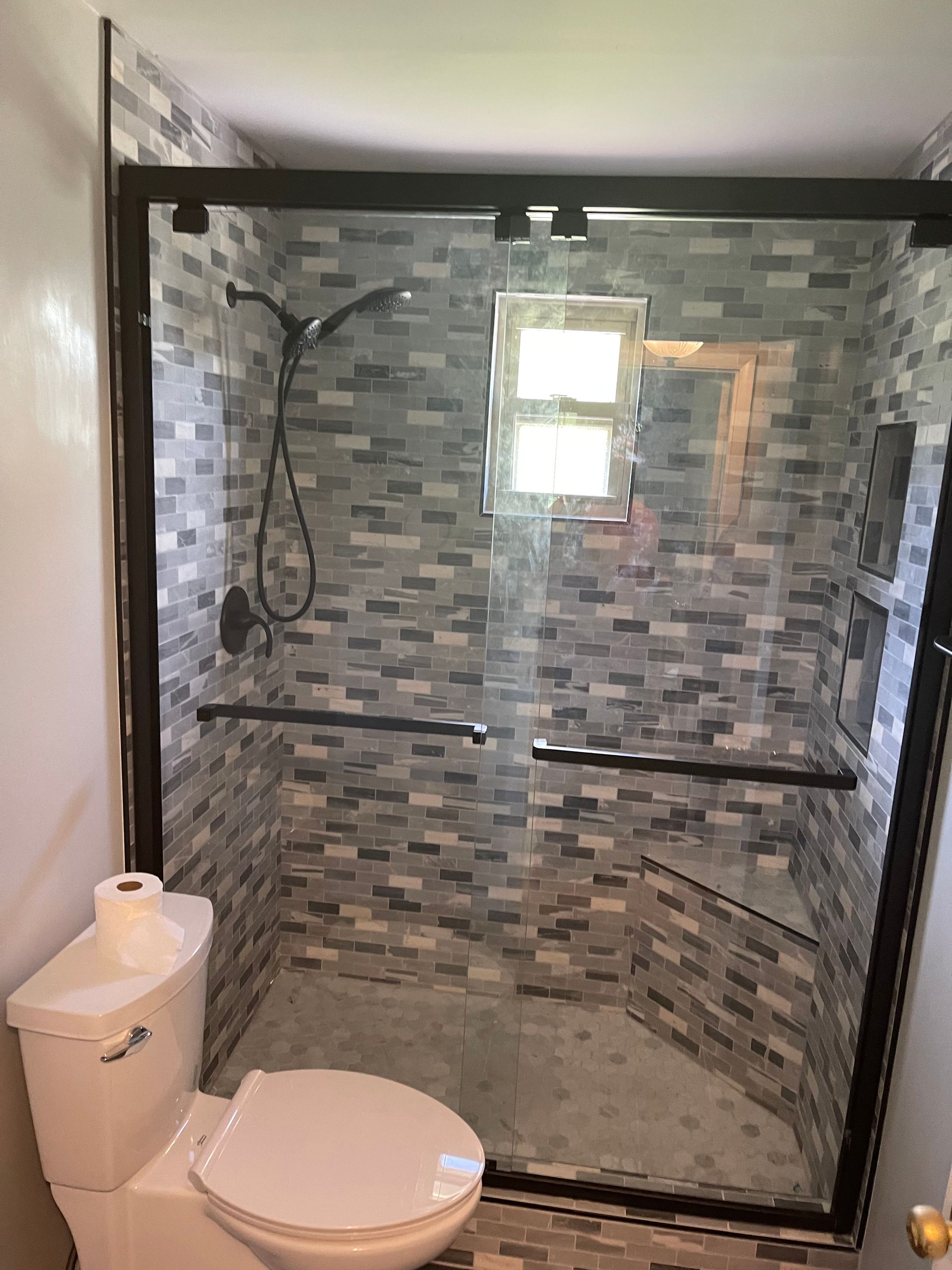 A bathroom with a toilet and a shower with a glass door.