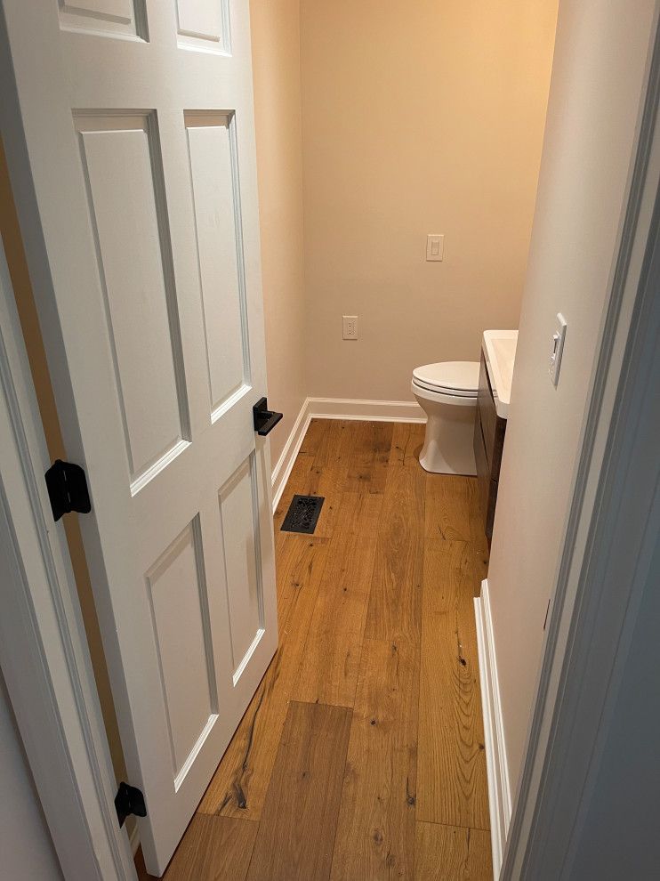 A bathroom with hardwood floors , a toilet and a sink.