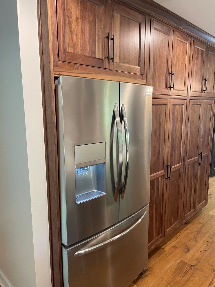 A stainless steel refrigerator in a kitchen with wooden cabinets.