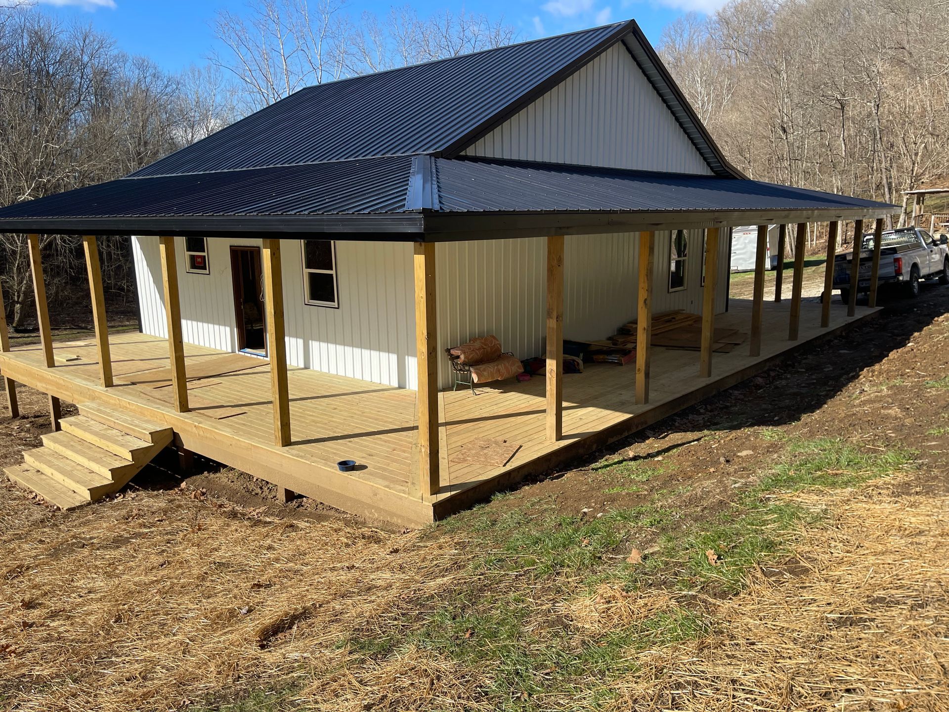 A white house with a black roof and a large porch.