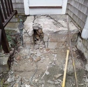 Collapsed concrete steps and rubble at an exterior entrance between two houses