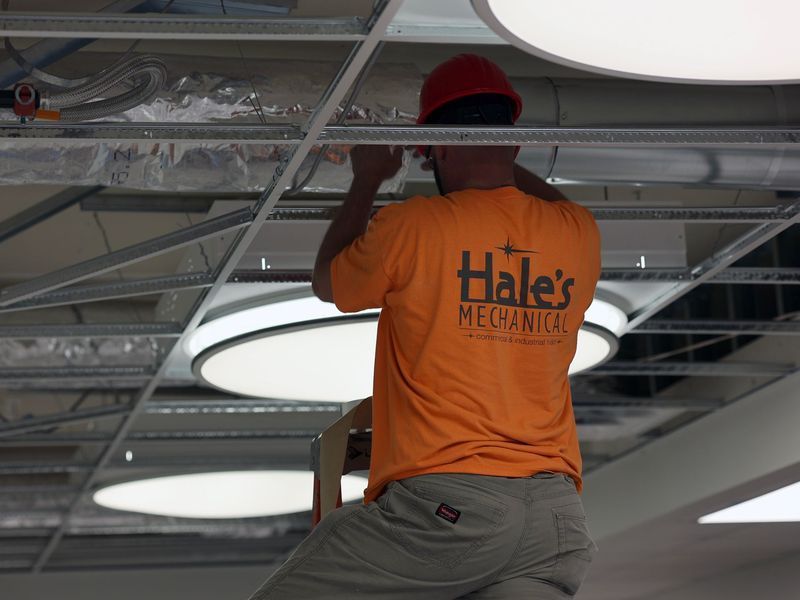 A worker wearing an orange shirt with 