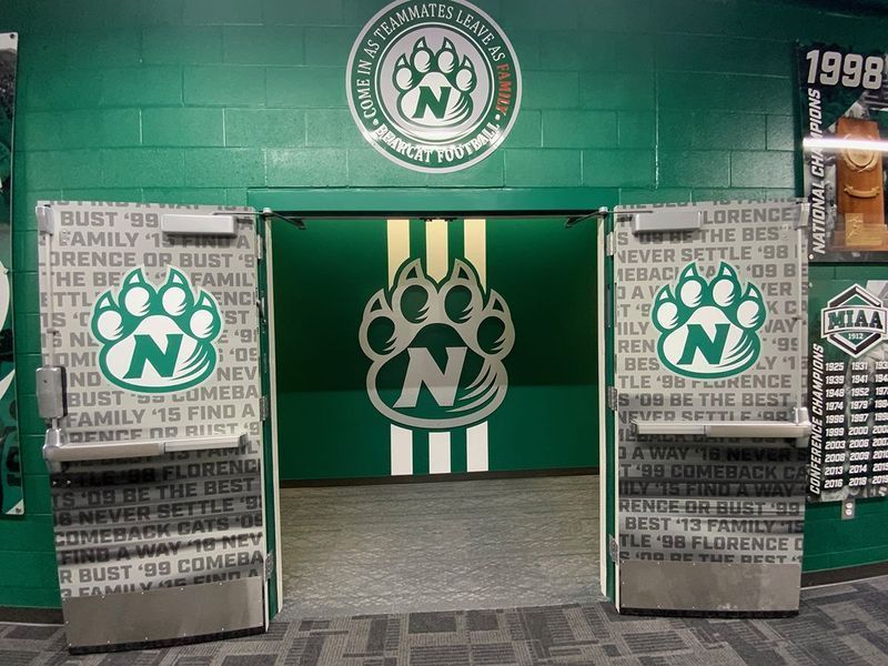 Green doorway with an 'N' paw print logo above and on the double doors, flanked by motivational text on the walls.