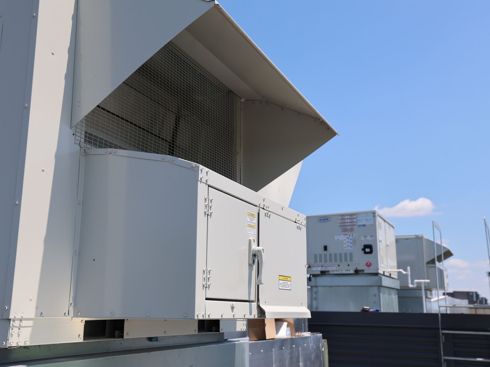 Large grey industrial rooftop HVAC cooling units against a clear blue sky.