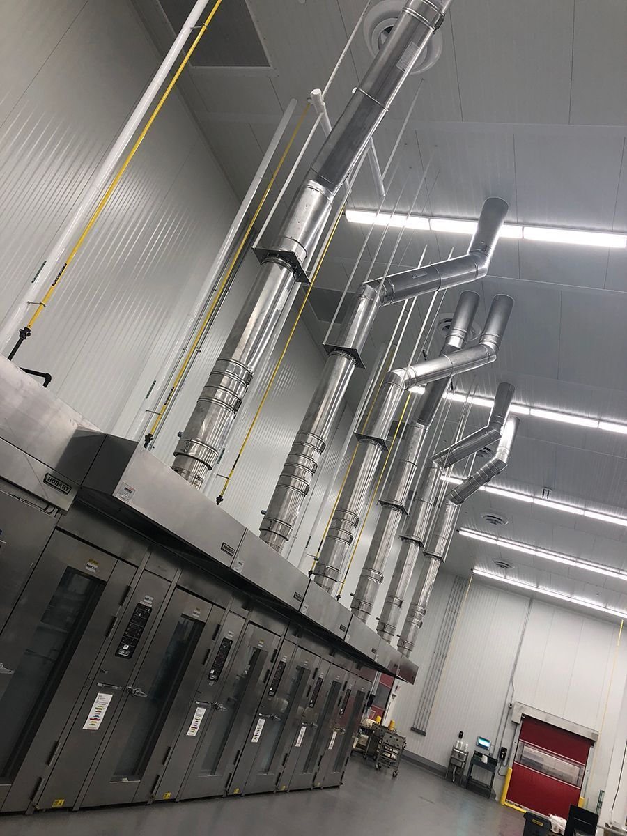 A row of stainless steel cabinets in a clean room, with ventilation ducts extending from the top towards the ceiling.