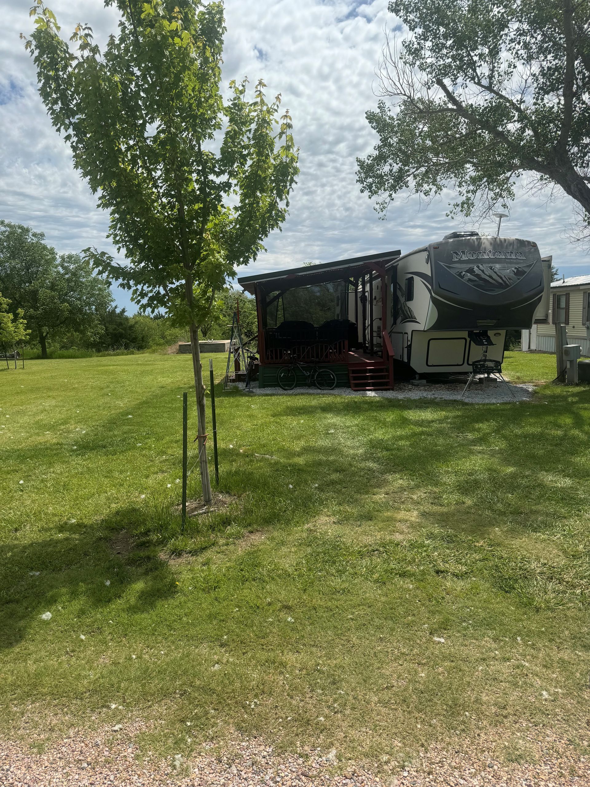 A rv is parked in a grassy field next to a tree.