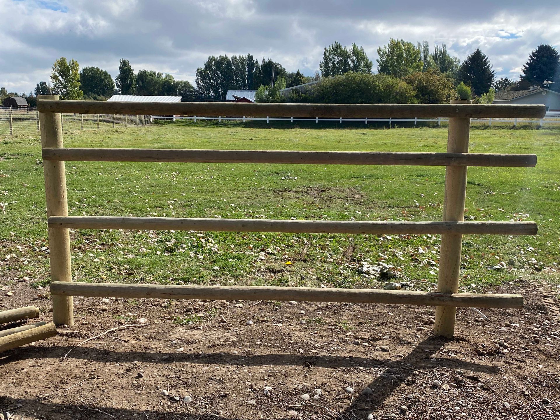 Wooden fence with three horizontal rails in a grassy field.